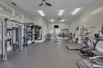 A spacious gym with a variety of equipment and a ceiling fan.
